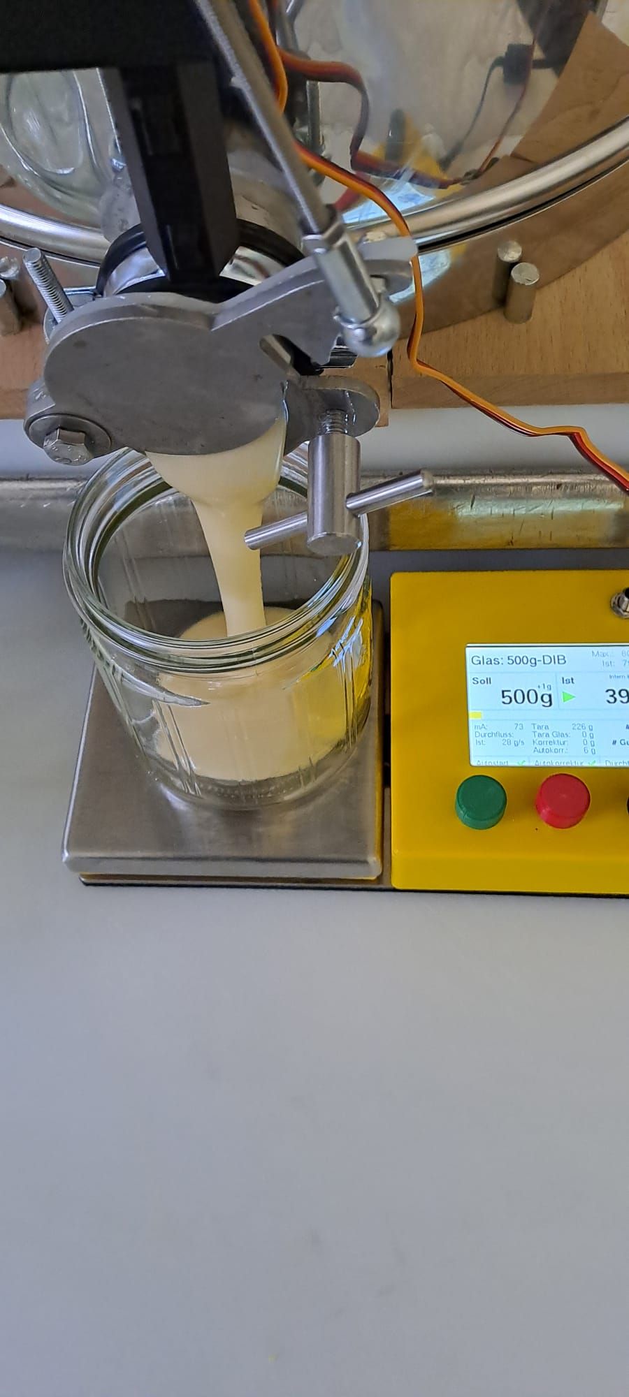 Cremiger Honig läuft aus der Abfüllmaschine in ein 500-g-Glas